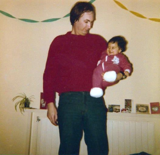 Ariane Sherine Juniper as a baby being held by her father