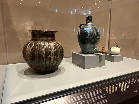 Musuem displays of pottery in glass cases, crafted headgear and
