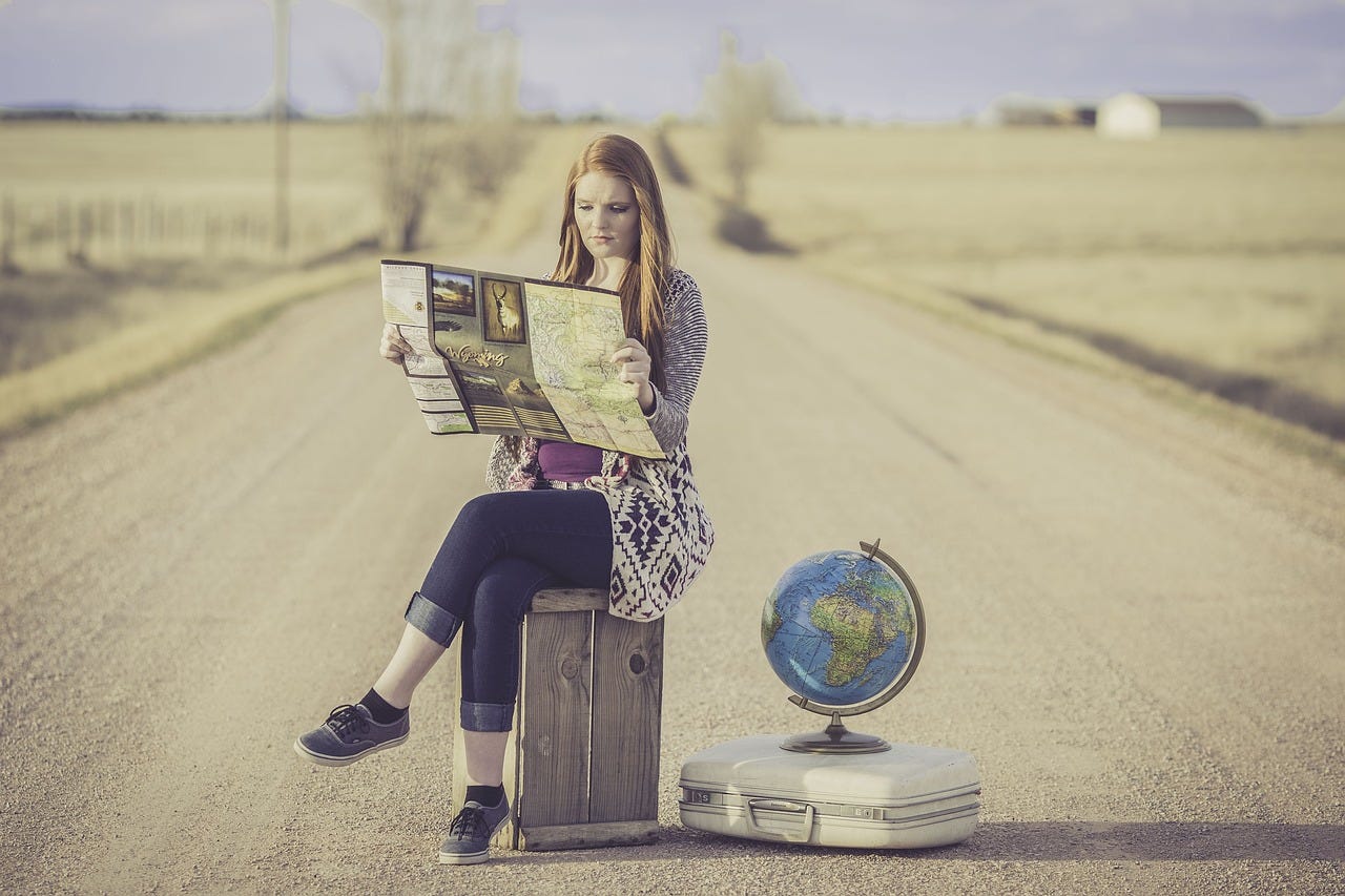 a women sitting in the middle of a desert road, holding a map in her hand, wondering what are the safest countries to visit as a female solo traveler