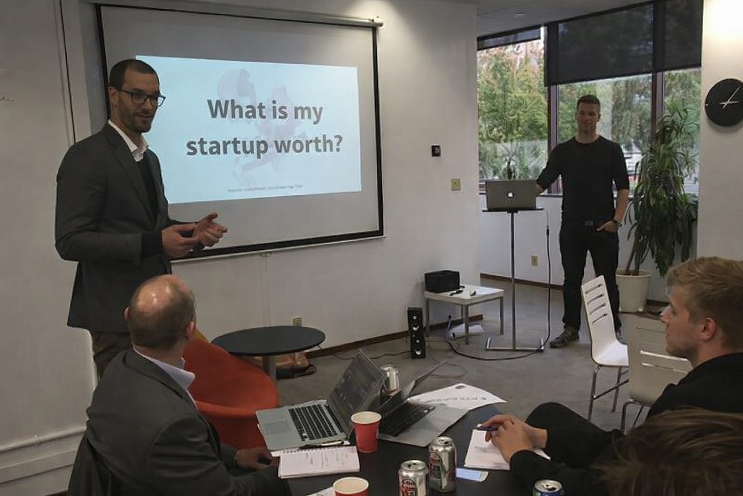 Startup founder presenting a slide asking what the company is worth to investors Startup founder presenting a slide asking what the company is worth to investors