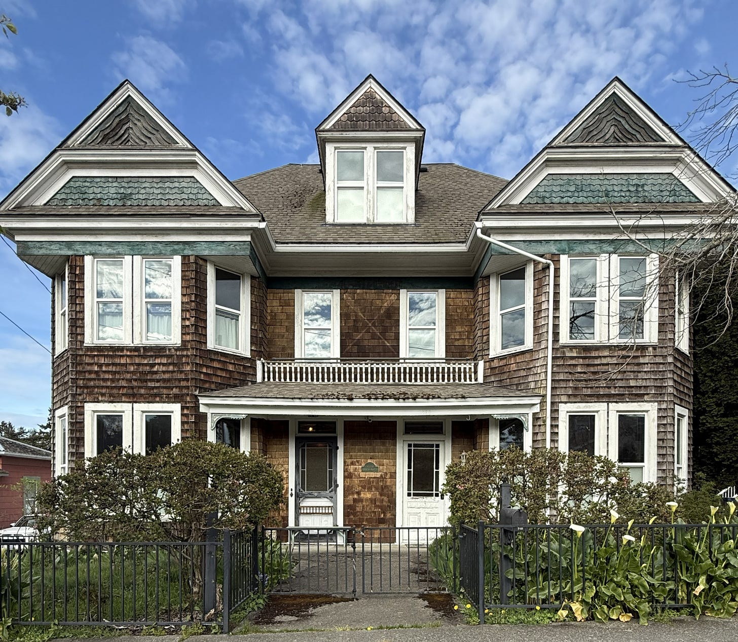 A symmetrical, 2-story duplex with cedar shakes in a variety of patterns