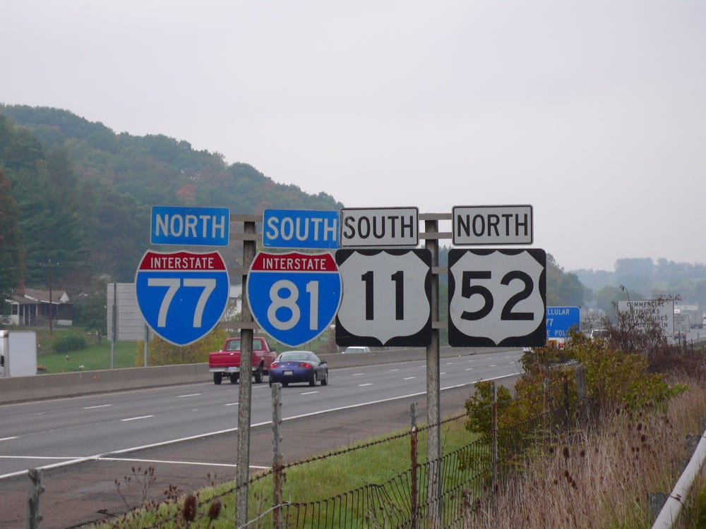 Photo of four freeway signs marking the same direction. Interstate 77 North, Interstate 81 South, U. S. 11 South, and U. S. 52 North.