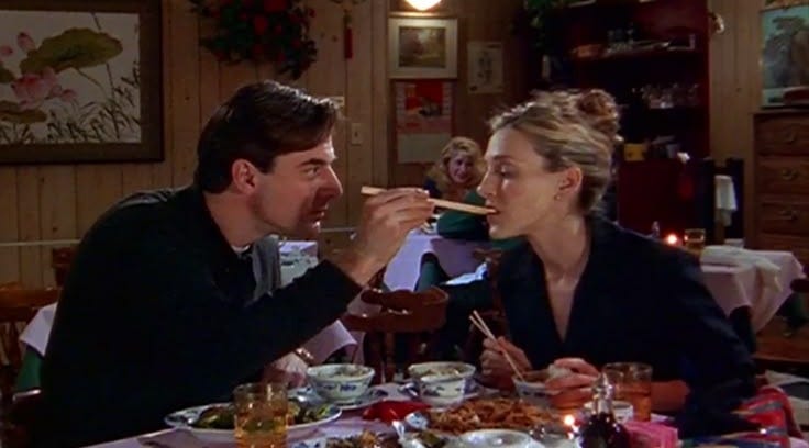 This may contain: a man and woman sitting at a table with food in front of them, eating