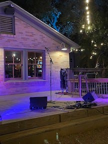 The neon sign for Radio Coffee and Beer, and the outdoor stage with mic stands and PA equipment, lit with blue light.