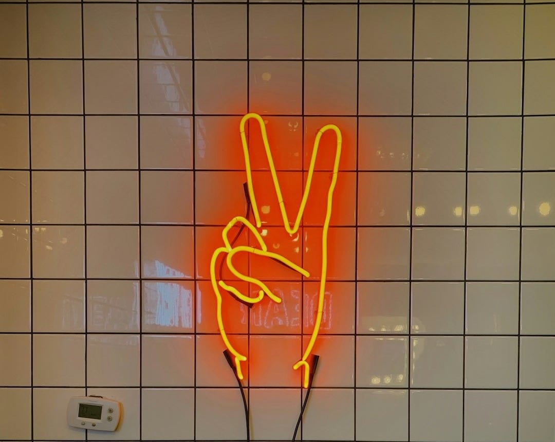 orange LED peace sign on tiled wall