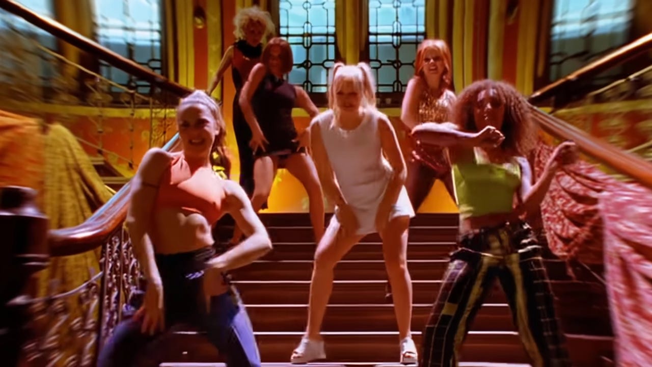 snapshot of the spice girls dancing on a staircase from the 90s music video for their hit song wannabe