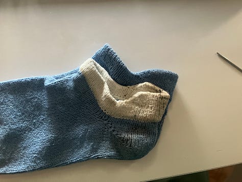 Photos showing the process of knitting and attaching new cuffs to a pair of blue handknit socks