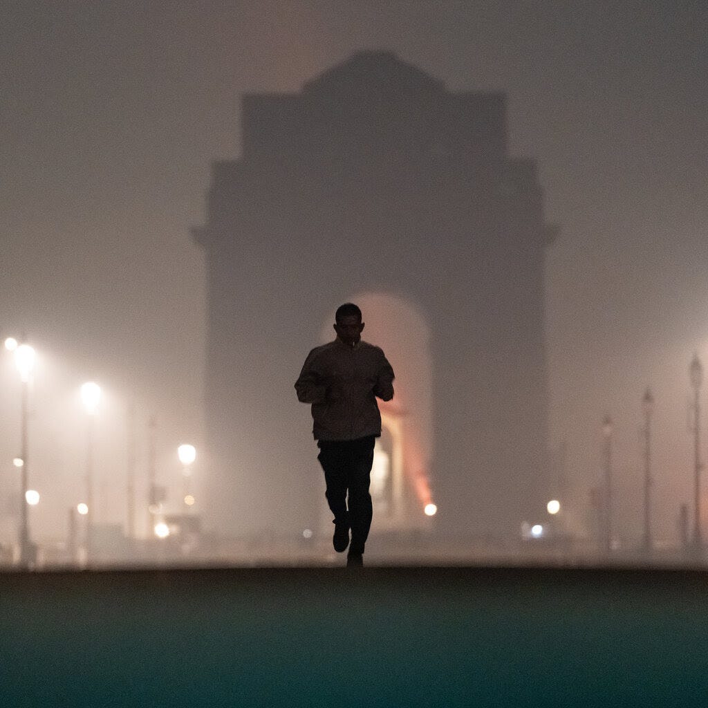 A person runs through dense fog early in the morning. Bright streetlights glow, and a dark archway is visible in the hazy background.
