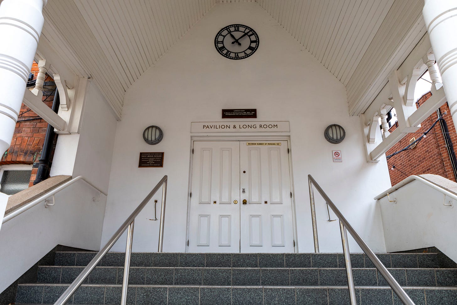 Steps leading up to the Long Room at Trent Bridge, with a white wall, door, and the Larwood Clock Steps leading up to the Long Room at Trent Bridge, with a white wall, door, and the Larwood Clock