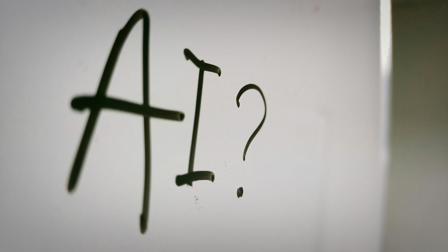 A dry-erase board with "AI?" written on it.
