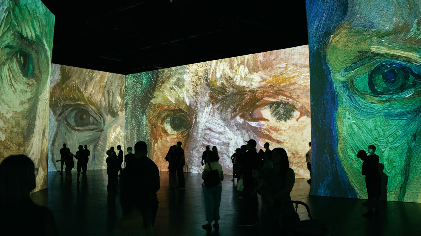 Close-up images of Vincent Van Gogh self portrait projected on big screens in a dark gallery.