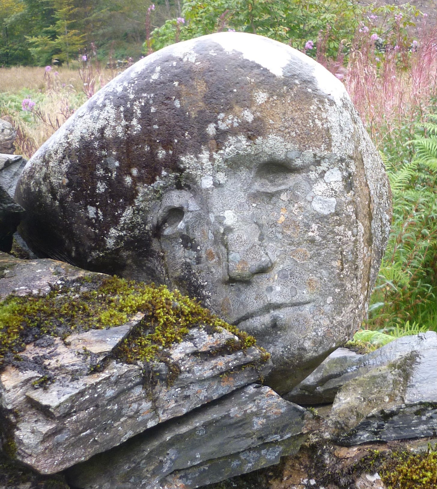 stone sculpted head outside with moss