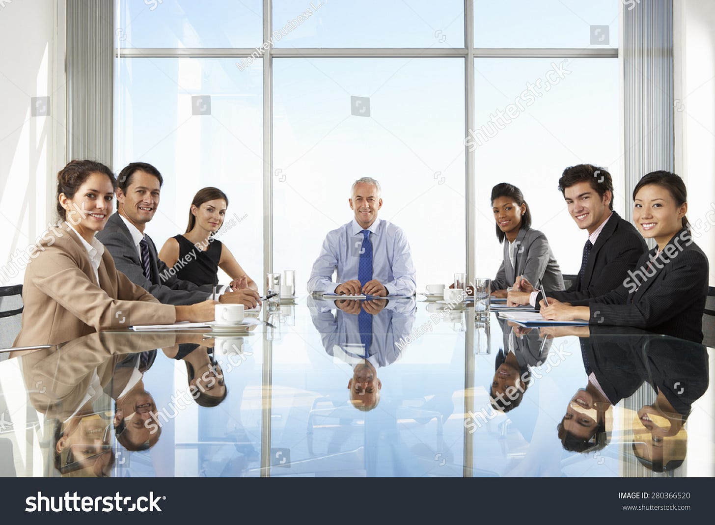 Group Of Business People Having Board Meeting Around Glass Table