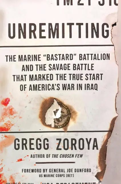 Book cover for Unremitting by Gregg Zoroya, featuring burned and blood-stained paper with bold text describing a Marine battalion and a pivotal battle in the Iraq War.