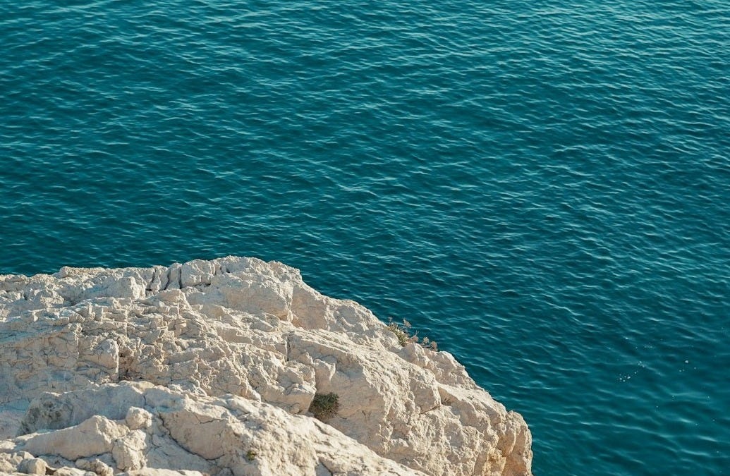 a person sitting on a rock near the water