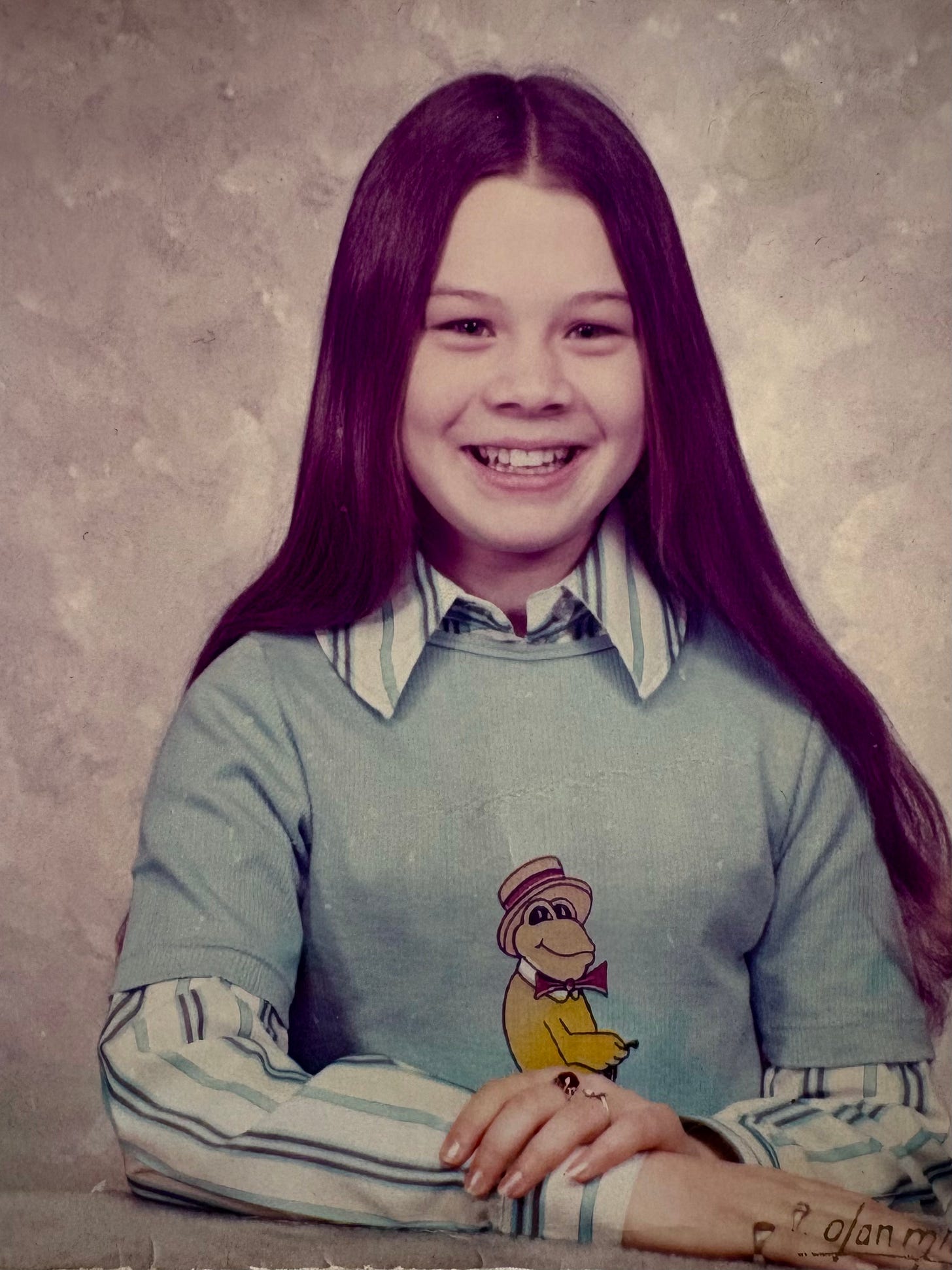 girl with long brown hair wearing shirt with frog