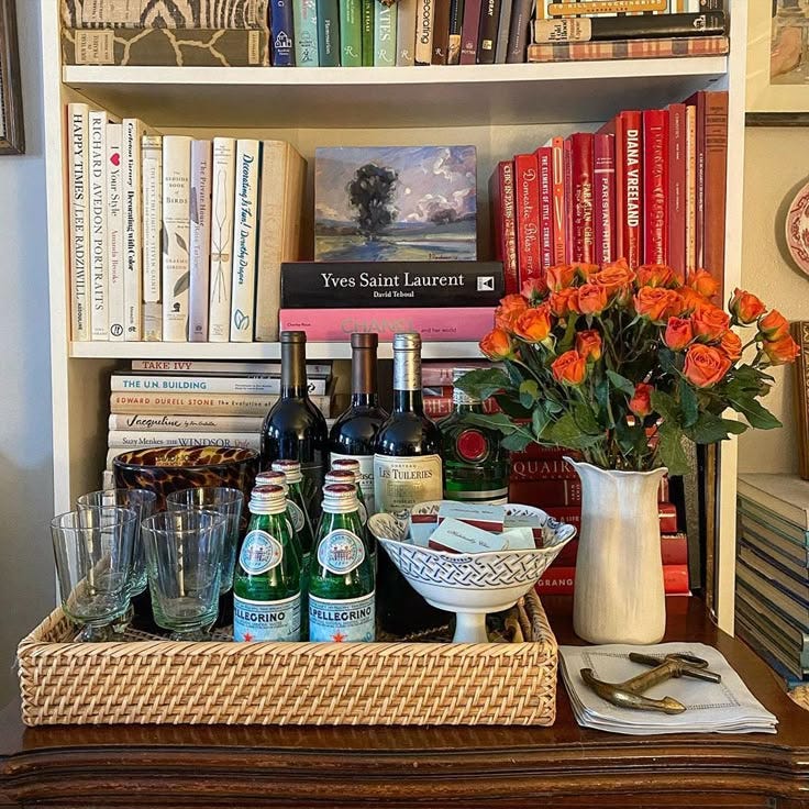 This may contain: there are many books and wine bottles on the shelf in front of the vases