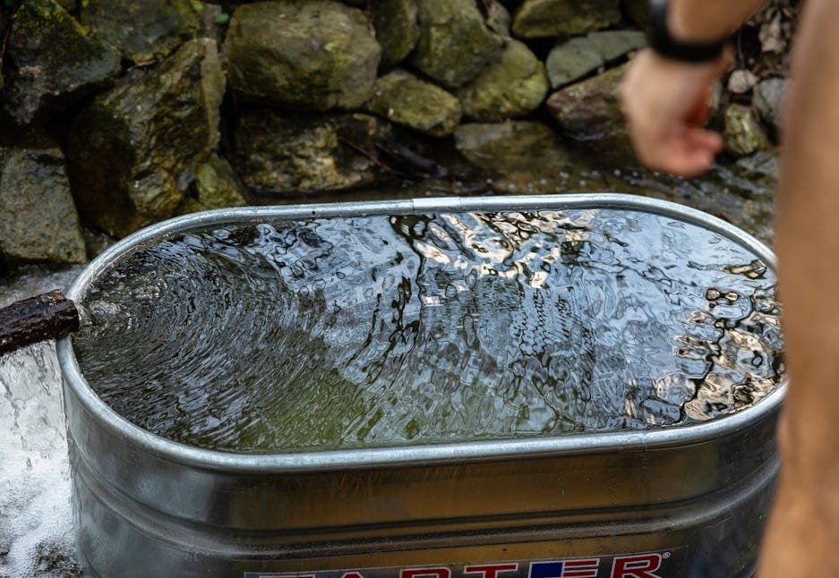 a man standing next to a metal tub filled with water
