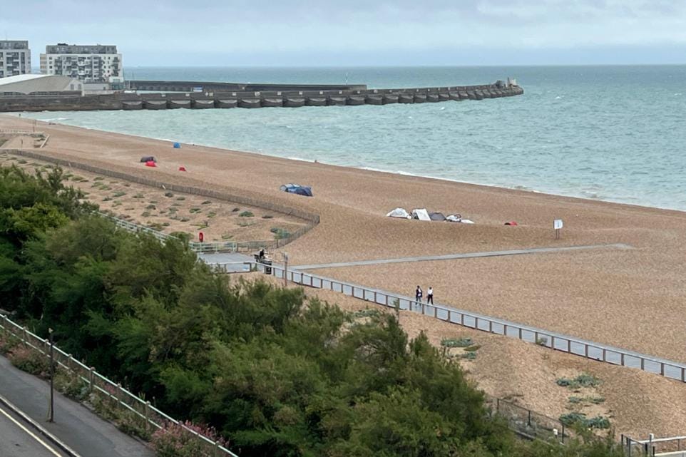 Several tents and windbreaks are pitched on Brighton’s shingle nudist beach near Black Rock, with a few people walking along the promenade and the sea wall in the distance. Several tents and windbreaks are pitched on Brighton’s shingle nudist beach near Black Rock, with a few people walking along the promenade and the sea wall in the distance.
