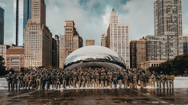 Photo of a large group of thugs in military cosplay gear standing in front of a public statue in Chicago