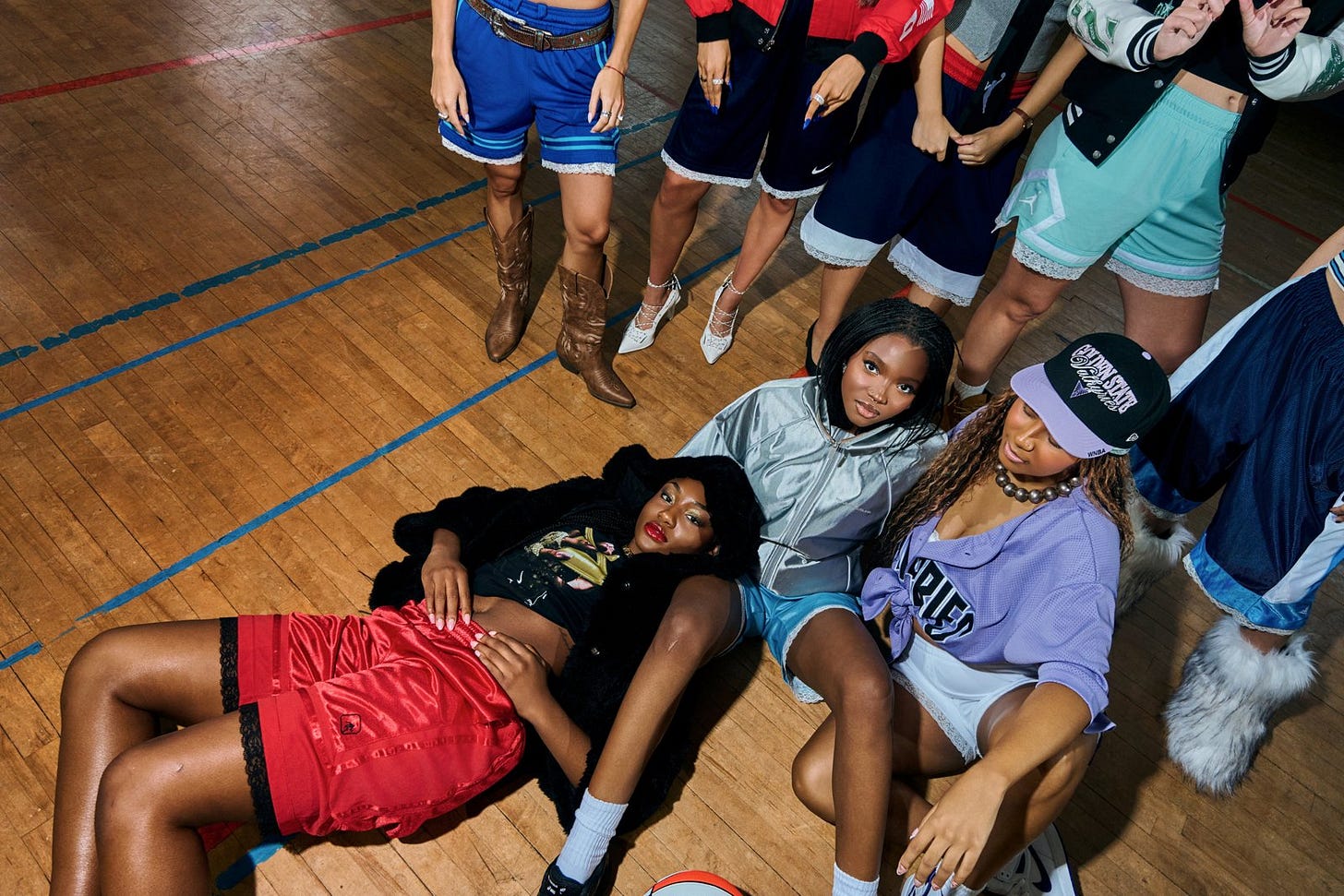 Women lounging on a basketball court in reworked vintage basketball shorts with lace trim Women lounging on a basketball court in reworked vintage basketball shorts with lace trim