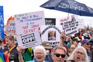 Demonstrators hold up signs during a "Hands Off!" protest against President Donald Trump at the Washington Monument in Washington, Saturday, April 5, 2025. (AP Photo/Jose Luis Magana)
