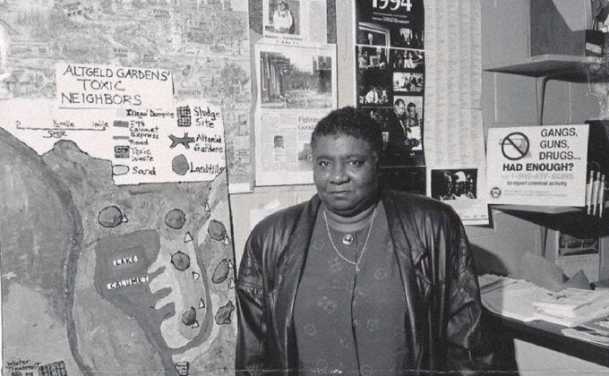 Hazel Johnson pose dans le local de People for Community Recovery. Derrière elle on peut lire certaines affiches ou livres / papiers voir « Algelf Gardens toxic neighbors »