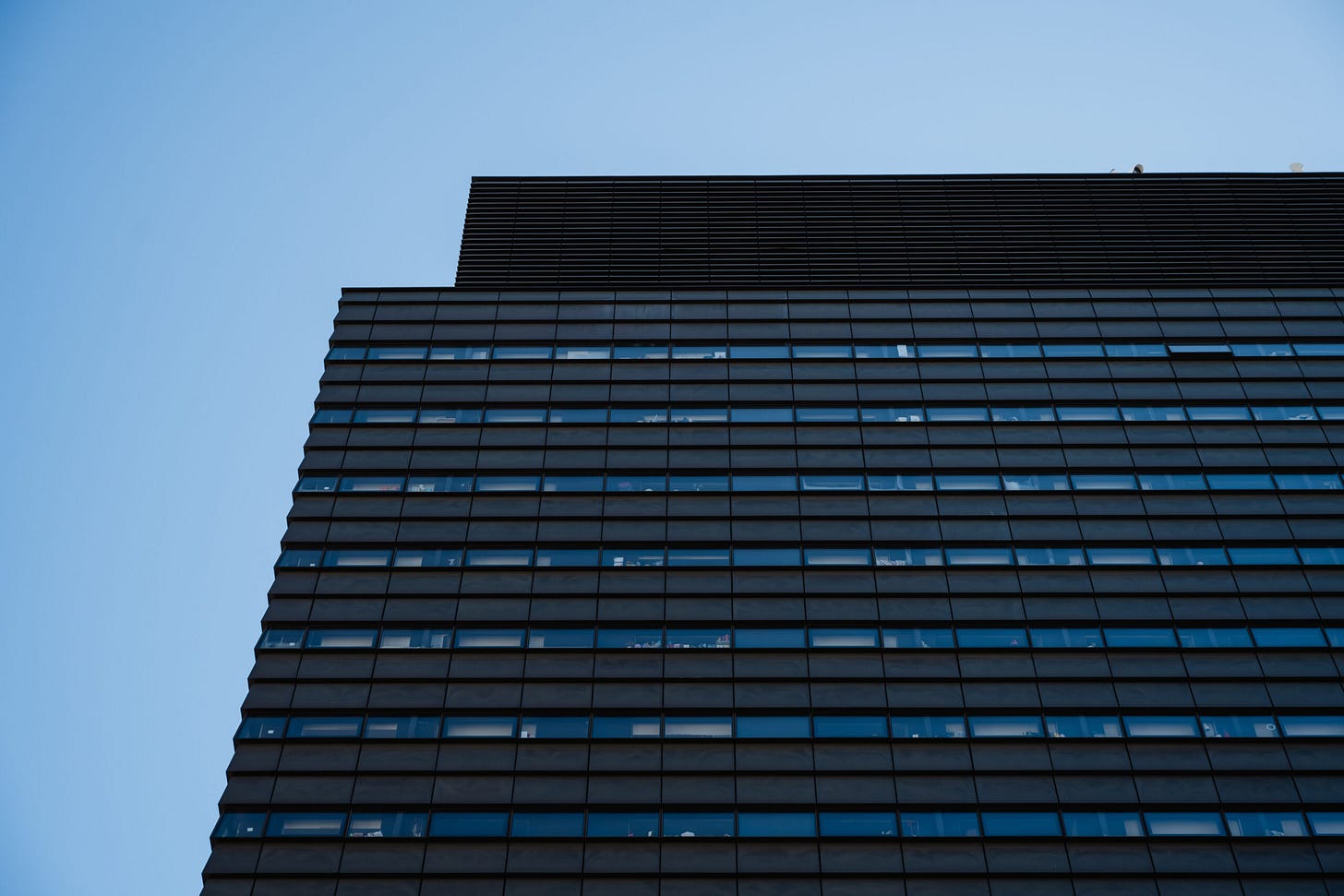 Top corner of The New School’s University Center with clear sky behind it.
