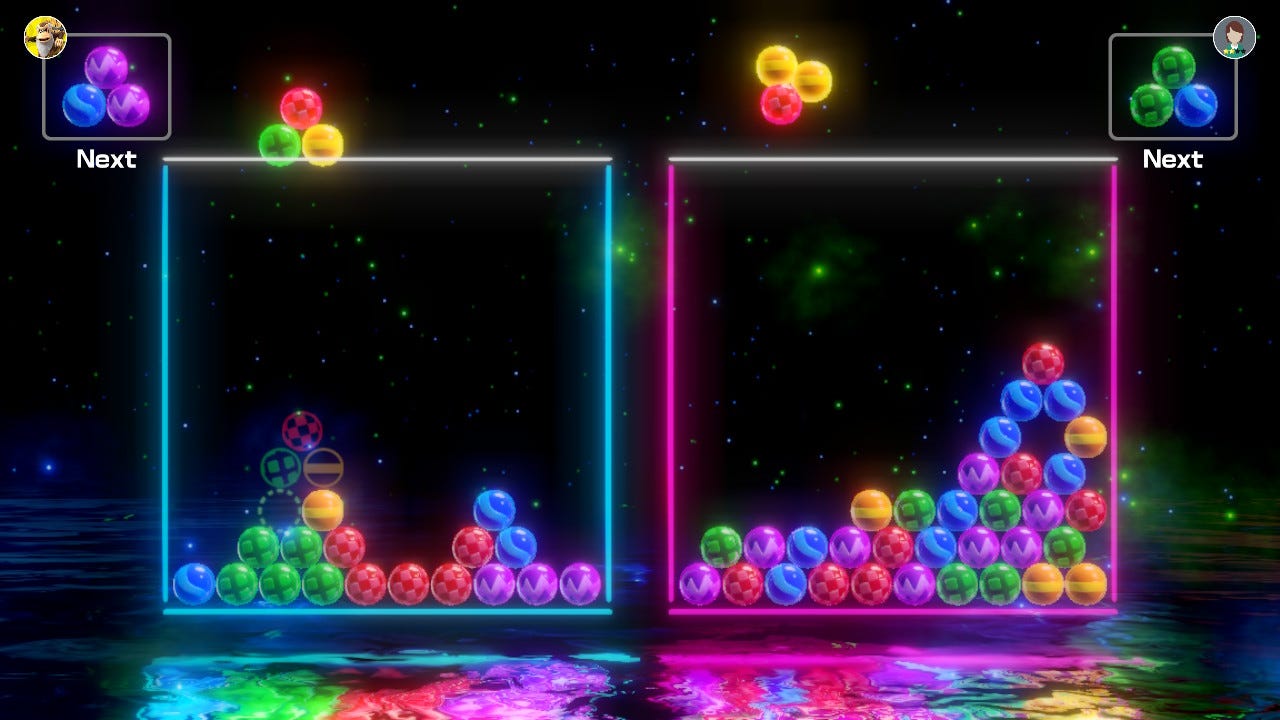 6-Ball Puzzle gameplay. Balls are laid in the field of play, with a "Next Box" in each corner showing each player what ball trio is coming next. The balls near the bottom of the screen are reflected in the water, and there is a starry background.