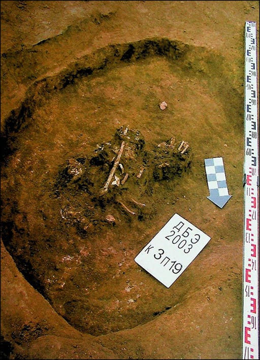 A burial site with visible skeletal remains and a labeled marker.