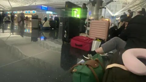 Stranded British Airway passengers with their luggage around them sit on the terminal floor at New York's John F.Kennedy airport on Friday morning Stranded British Airway passengers with their luggage around them sit on the terminal floor at New York's John F.Kennedy airport on Friday morning