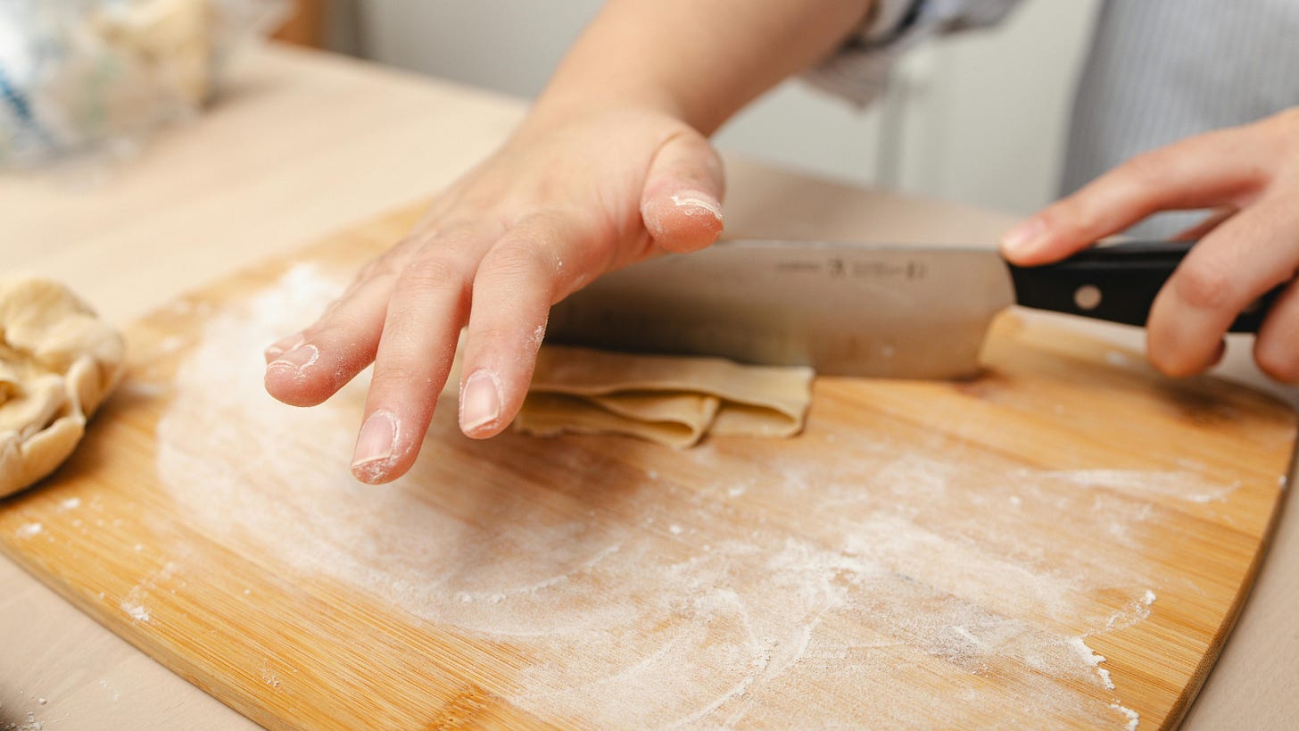 Homemade pasta dough being rolled by hand with a rolling pin for fresh pasta without a machine