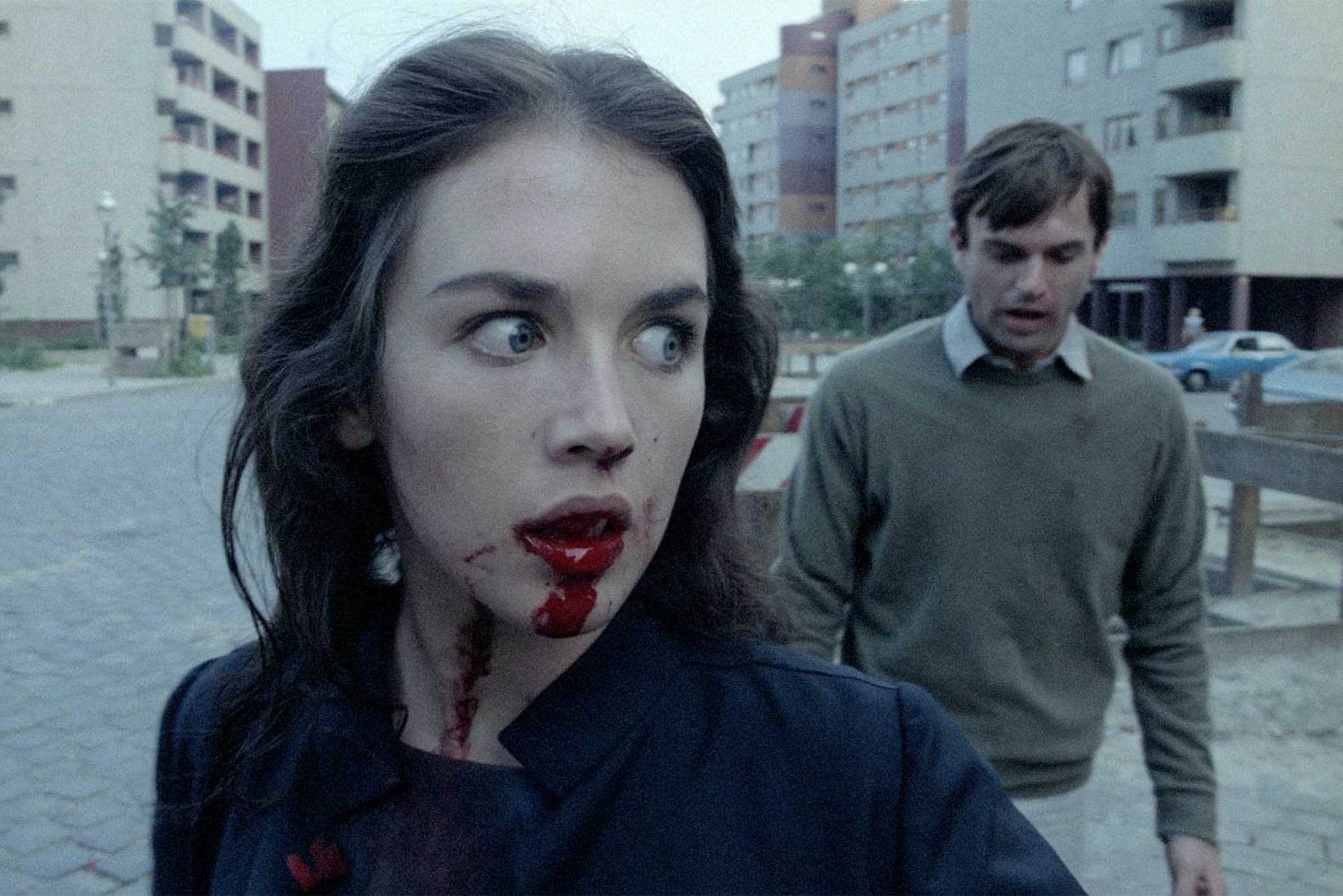A picture from Posession where Isabelle Adjani has blooding dripping from her mouth and Sam Neill looks distraught. They are in the middle of a street in Berlin.