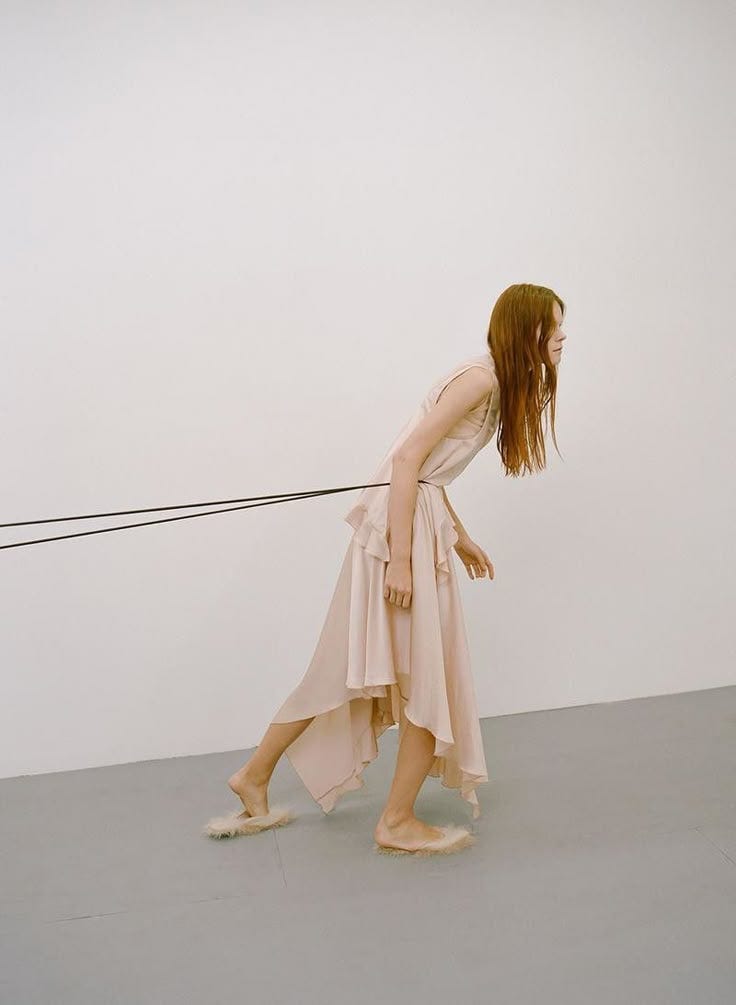 This may contain: a woman walking across a white floor next to a wall with a string attached to it