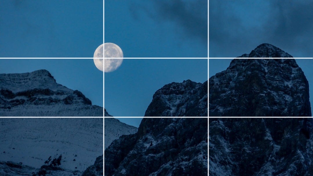 a full moon is seen above a snowy mountain