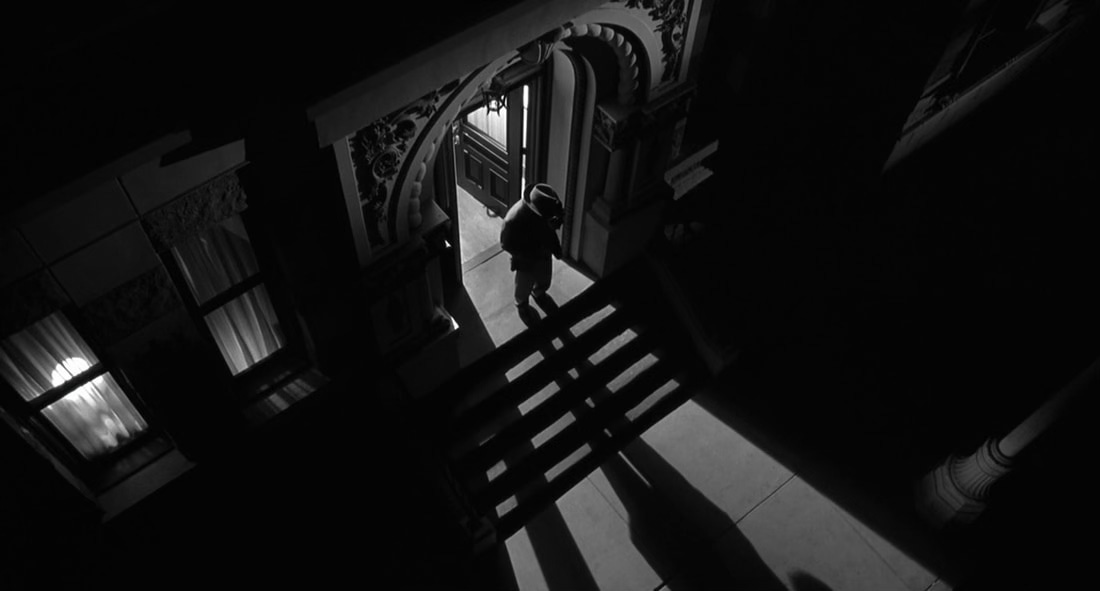 A b&w movie still with a man standing in a shadowy doorway