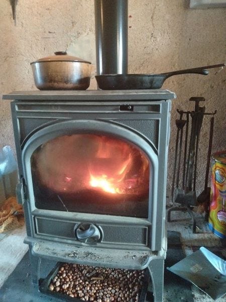 Wood-fired stove with food cooking on top.