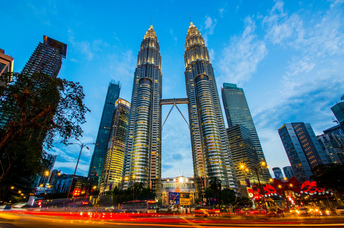 A vibrant long-exposure evening photograph of the illuminated Petronas Twin Towers in Kuala Lumpur, Malaysia, with bright light trails from city traffic in the foreground. The image highlights Malaysia's status as Southeast Asia's most-visited country in early 2026 amid its "Visit Malaysia 2026" tourism campaign. A vibrant long-exposure evening photograph of the illuminated Petronas Twin Towers in Kuala Lumpur, Malaysia, with bright light trails from city traffic in the foreground. The image highlights Malaysia's status as Southeast Asia's most-visited country in early 2026 amid its "Visit Malaysia 2026" tourism campaign.