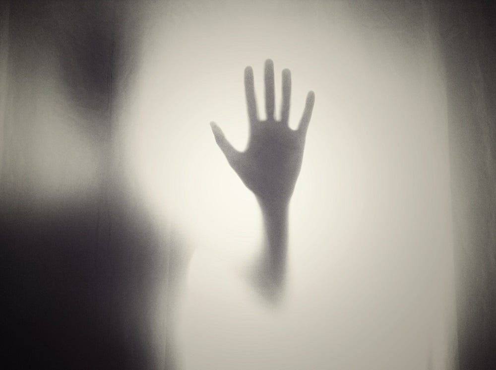 A hand on glass in the mist