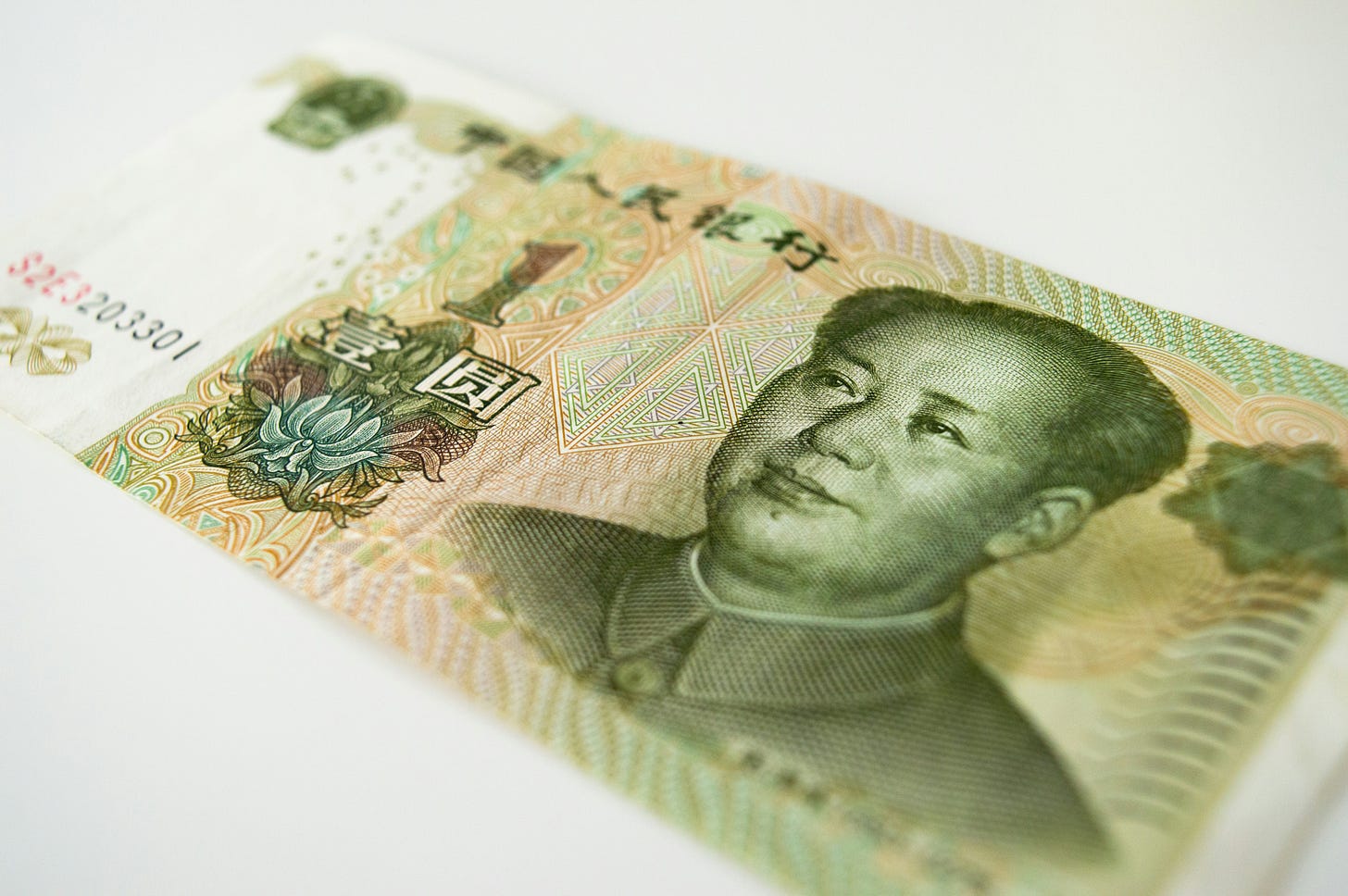 fundo branco com nota de 1 yuan no centro, com foco no rosto de Mao Zedong estampado na foto