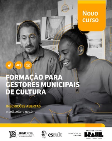 #descrevemospravocê  Card de divulgação do novo curso Formação para Gestores Municipais de Cultura, com inscrições abertas pelo site escult.cultura.gov.br. A iniciativa é promovida pelo CECULT/UFRB (Centro de Cultura, Linguagens e Tecnologias Aplicadas da Universidade Federal do Recôncavo da Bahia), por meio da plataforma Escult, com apoio do Ministério da Cultura e do Governo Federal do Brasil — União e Reconstrução.  O card tem fundo em escala de cinza, com destaque para elementos gráficos em amarelo e laranja, que dão cor e ênfase às informações principais. No topo direito, há um bloco laranja com cantos arredondados contendo o texto "Novo curso". Abaixo, em letras grandes brancas, está o título do curso. Logo acima, três ícones em bolhas amarelas indicam acessibilidade com os símbolos de audiodescrição, Libras e legenda.  A imagem central é uma fotografia em preto e branco de duas pessoas sorrindo enquanto olham juntas para algo fora do quadro, possivelmente um projeto. À esquerda, há um homem branco, de cabelos e barba claros, com expressão atenta. À direita, uma mulher negra, de cabelos presos em coque, com um sorriso aberto, segura uma caneta e interage com o colega. Ao fundo, vê-se um ambiente de escritório ou sala de aula, com papéis, quadros e anotações na parede.  No rodapé, sobre uma faixa amarela, estão os logotipos das instituições organizadoras e apoiadoras.