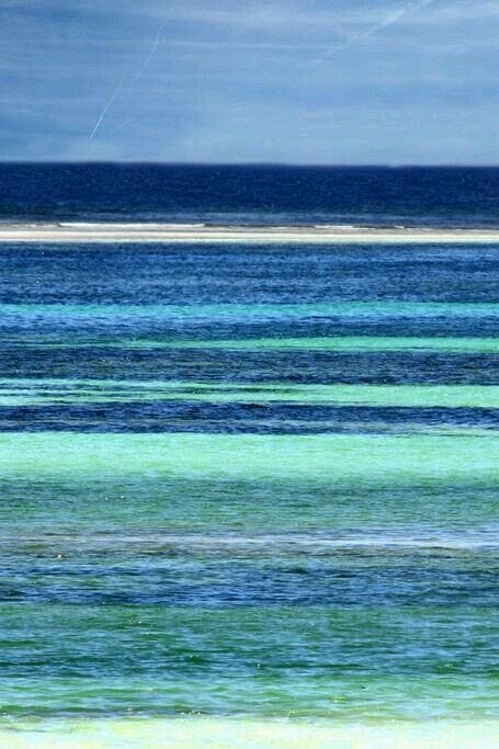 This may contain: a person kite surfing in the ocean on a sunny day with blue sky and green water This may contain: a person kite surfing in the ocean on a sunny day with blue sky and green water