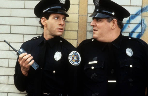 Steve Guttenberg looks to another cop in a scene from the film 'Police Academy 2: Their First Assignment', 1985.