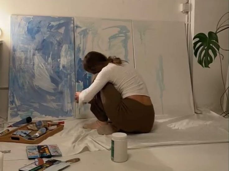 This may contain: a woman is sitting on the floor painting