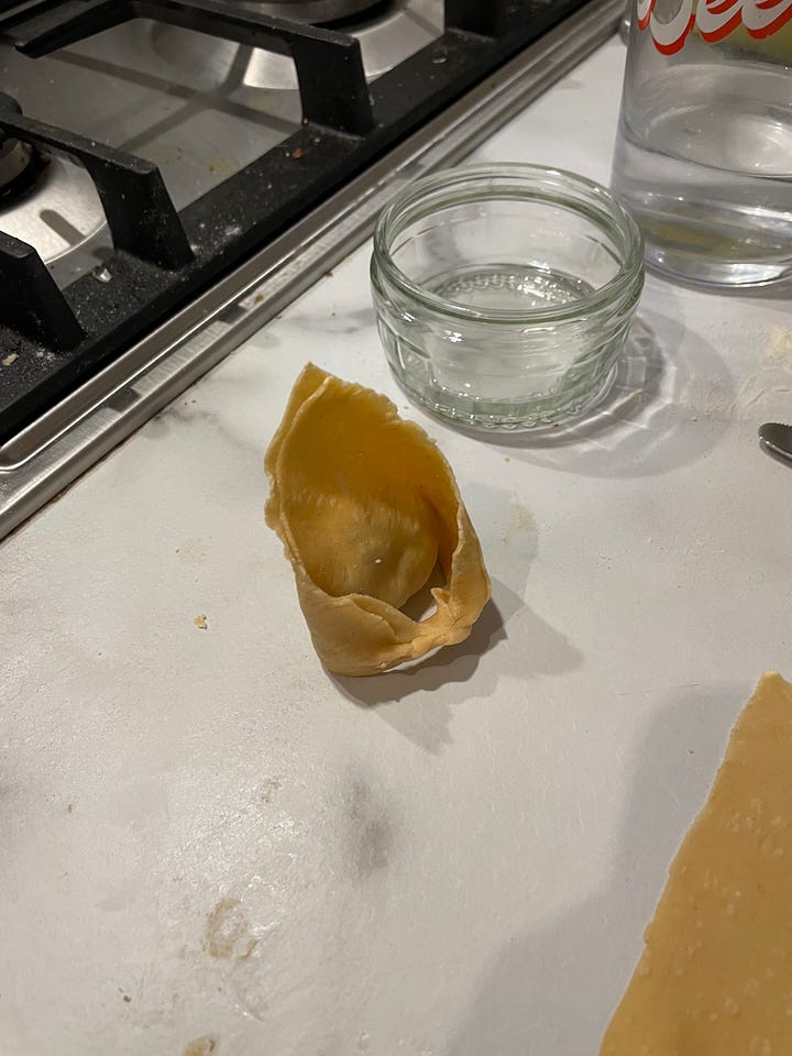 Steps for making tortellini from fresh using a pasta machine illustrated. The pasta is rolled before cut into squares, with a small amount of filling added and then folded into a triangle before the bottom two corners are tied around
