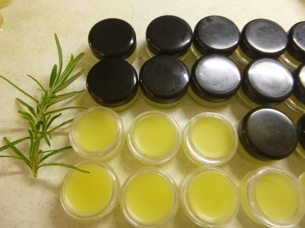 Small jars with and without tops containing rose and marigold lip balm