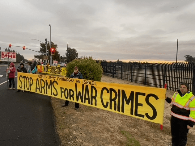 A group of people holding a yellow banner

Description automatically generated