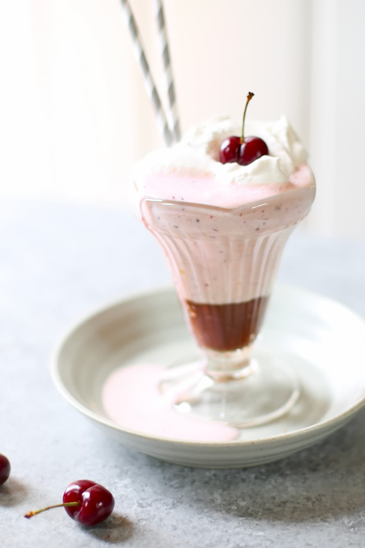 a cherry milkshake on a table with fresh cherries next to it