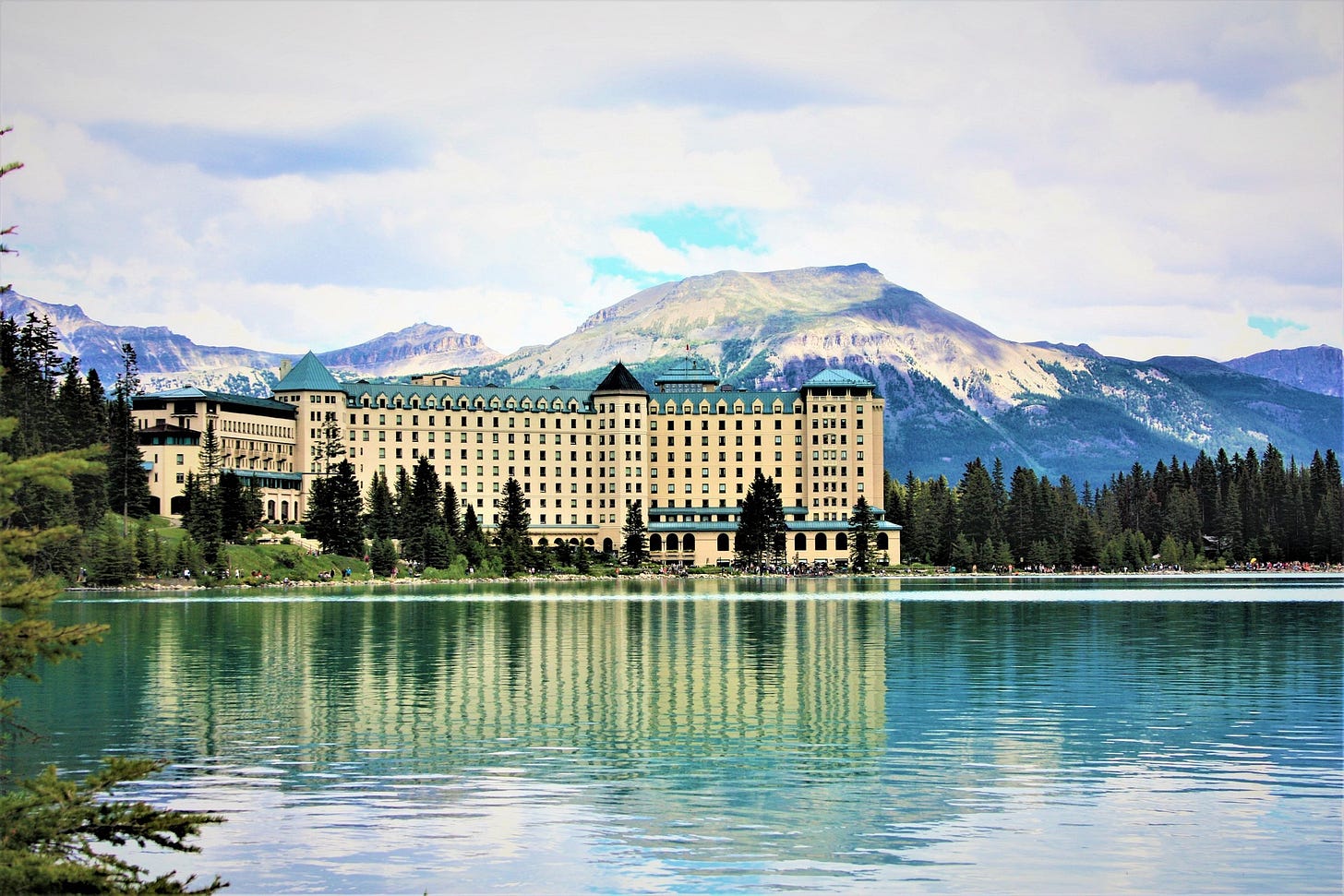 Fairmont Chateau Lake Louise hotel on shoreline with stunning mountain backdrop, iconic Banff accommodation for families