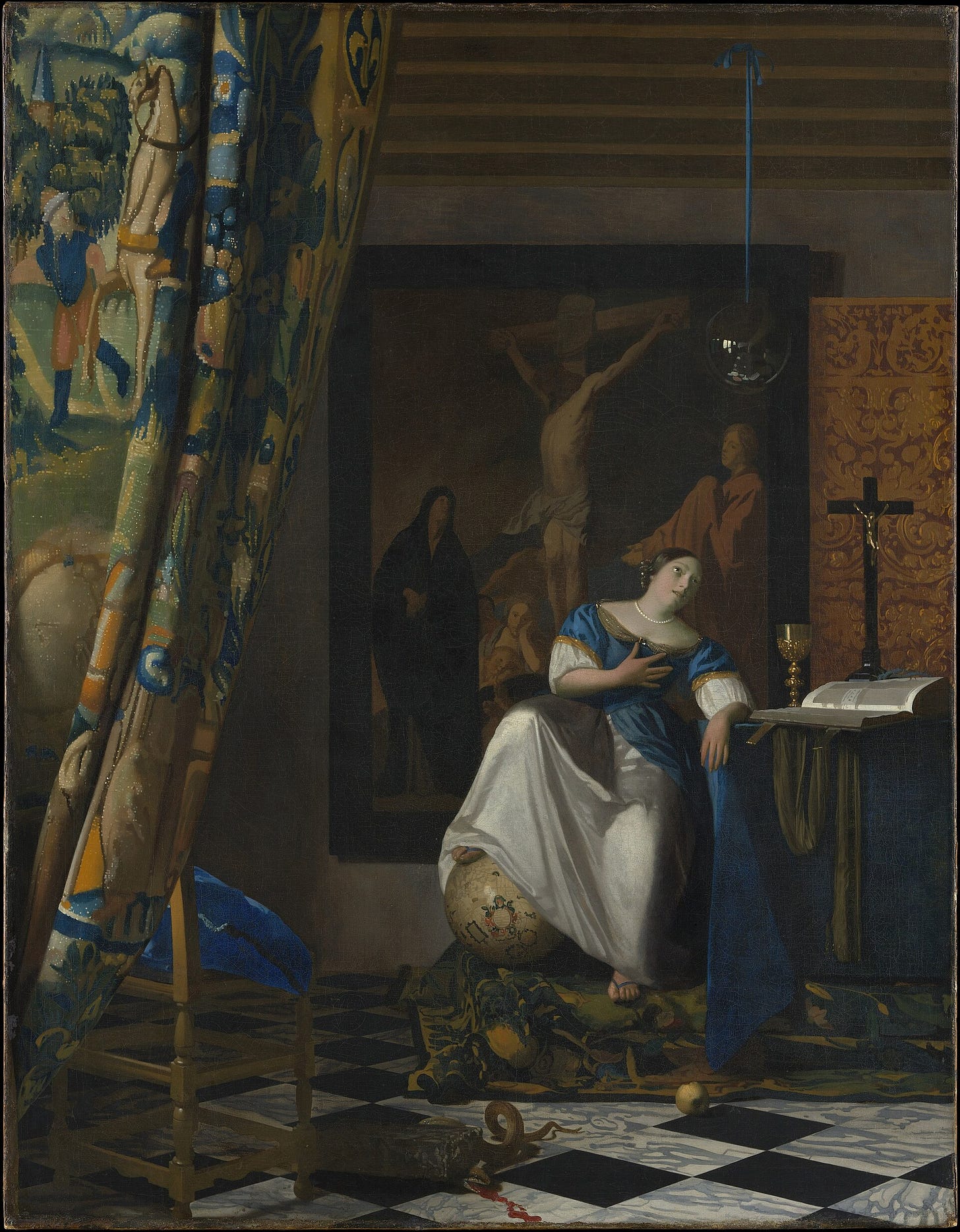 A woman in blue and white satin sits with one foot on a globe and a hand on her chest, gazing at a glass sphere that hangs from the ceiling, beside a table with a chalice, a crucifix and an open book, in front of a large Crucifixion painting and a pulled-back tapestry curtain.